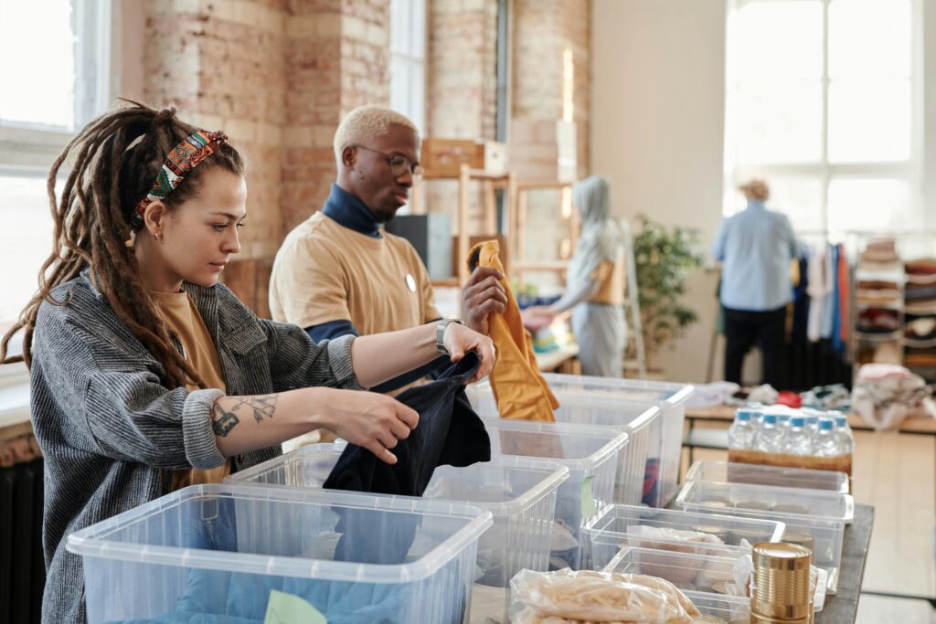 Foster care volunteers sorting clothes in a well-lit room with brick walls, emphasizing organization and community service.